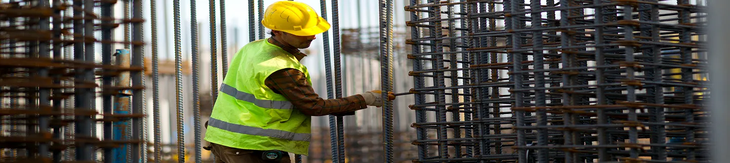 Construction worker installing reinforcement among rebar cages